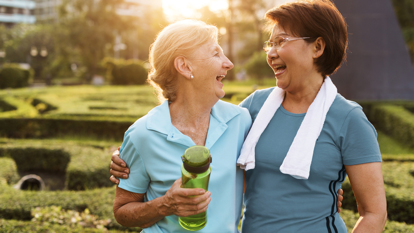 Two happy senior women friends exercising in the park during a morning